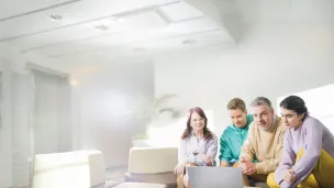 Neljä ihmistä katsoo tietokonetta